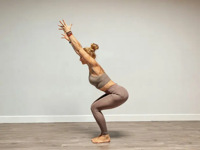 a woman doing a yoga pose on a wooden floor